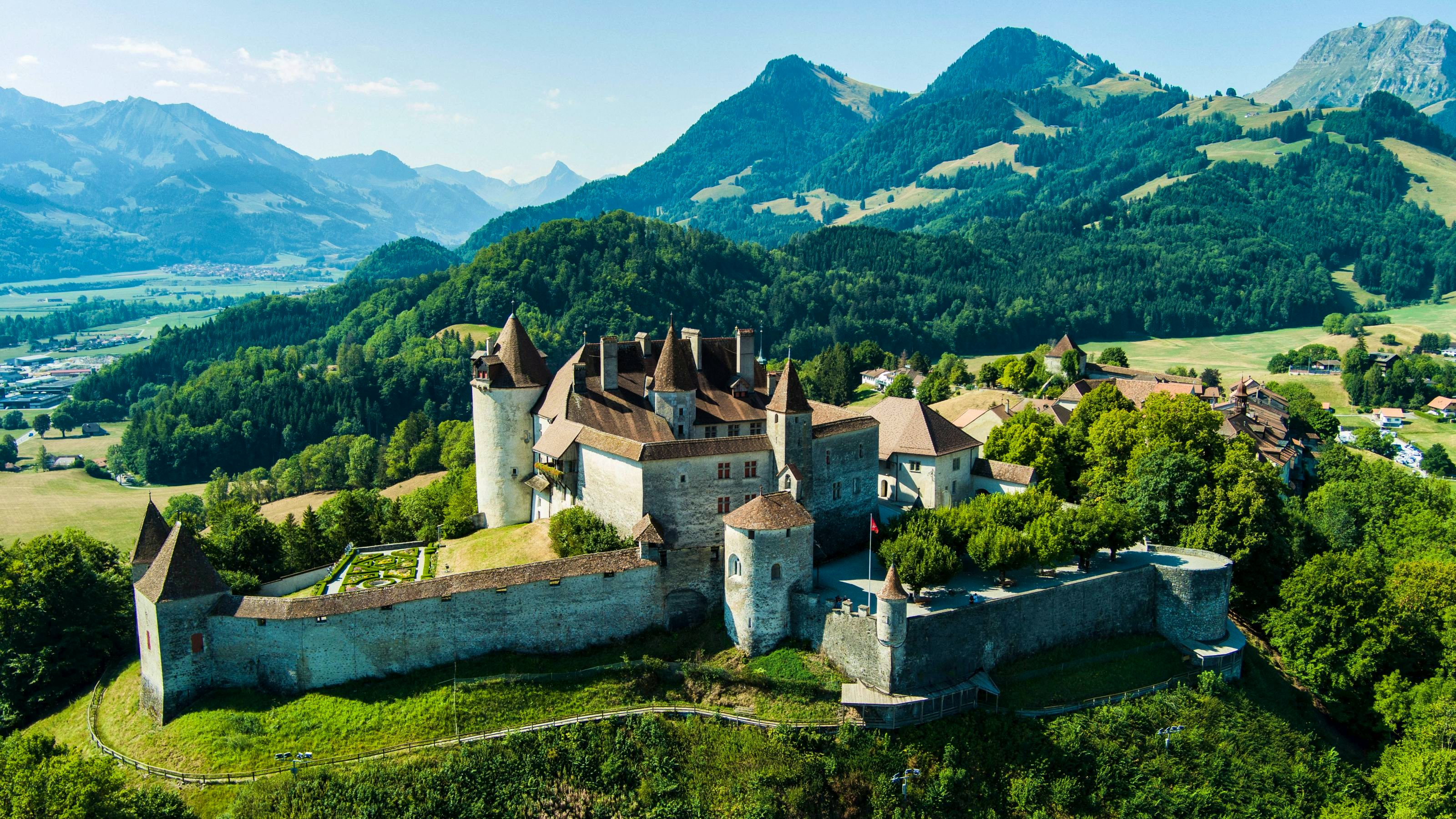 Das Schloss Gruyères von oben gesehen mit Bergen im Hintergrund.