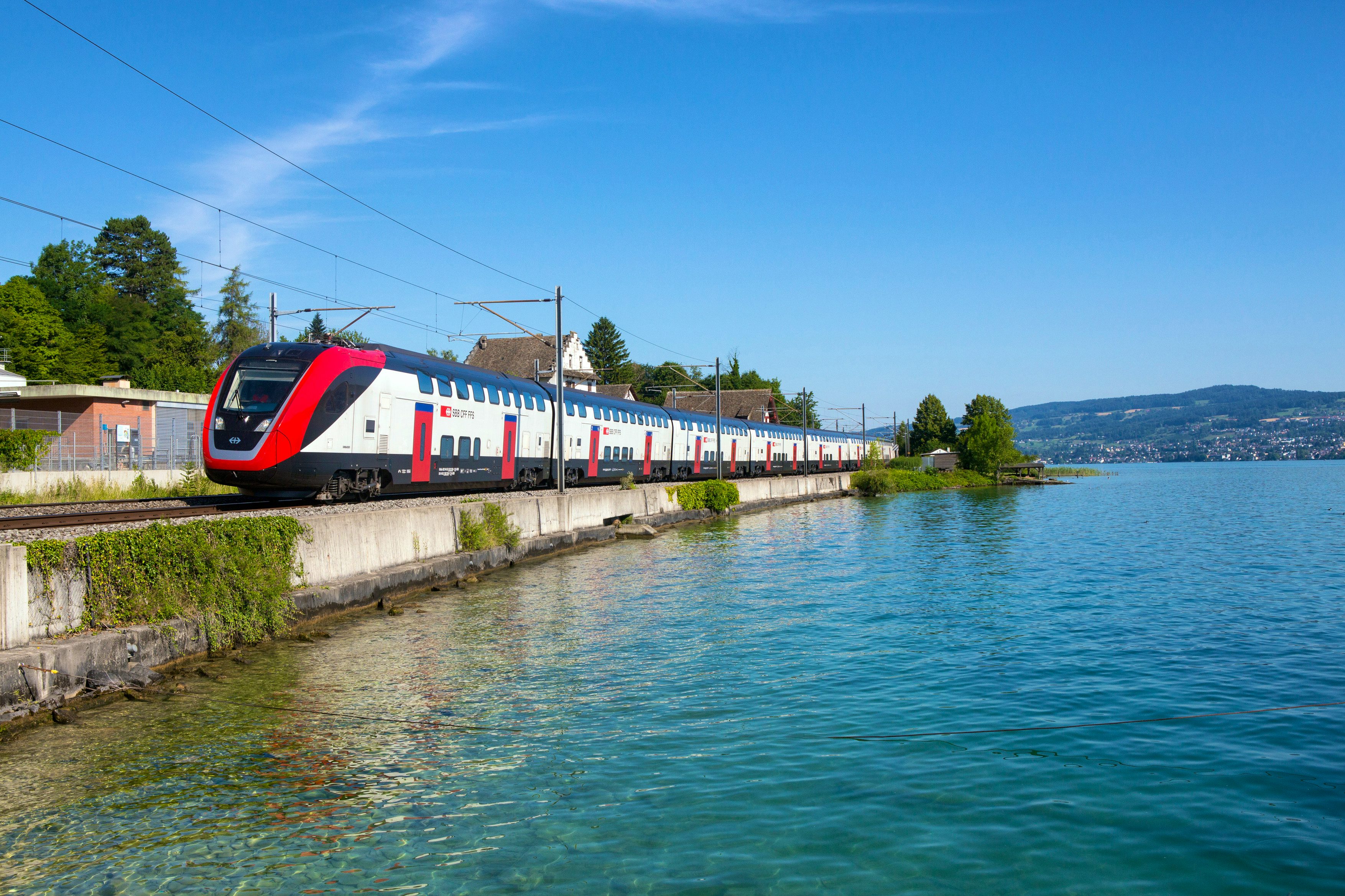 Il bipiano TLP circola in una giornata soleggiata a Richterswil, sul lago di Zurigo. Il lago rimane alla sinistra del treno. 